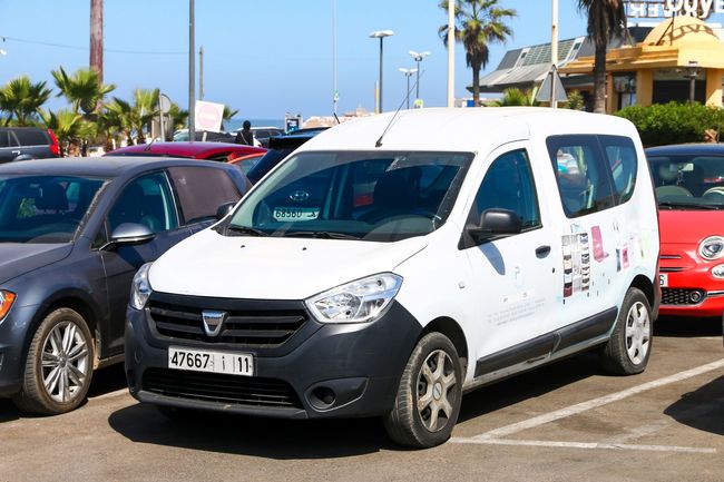 Una furgoneta blanca con matrícula gpe21 está estacionada en un estacionamiento