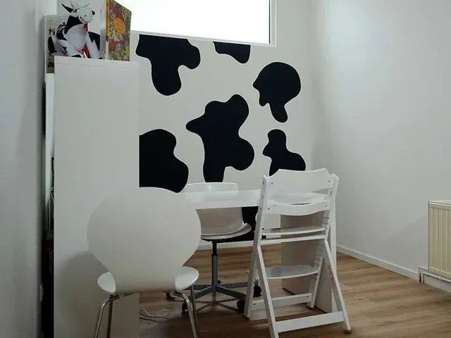 Weißer Essbereich mit Wanddekor und Stühlen im Kuhmuster.