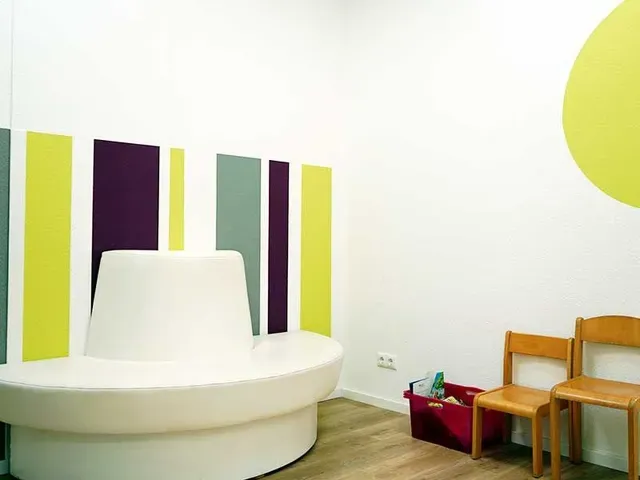 Wartezimmer mit weißer Bank, bunt gestreifter Wand, zwei Stühlen und einem gelben Kreis.