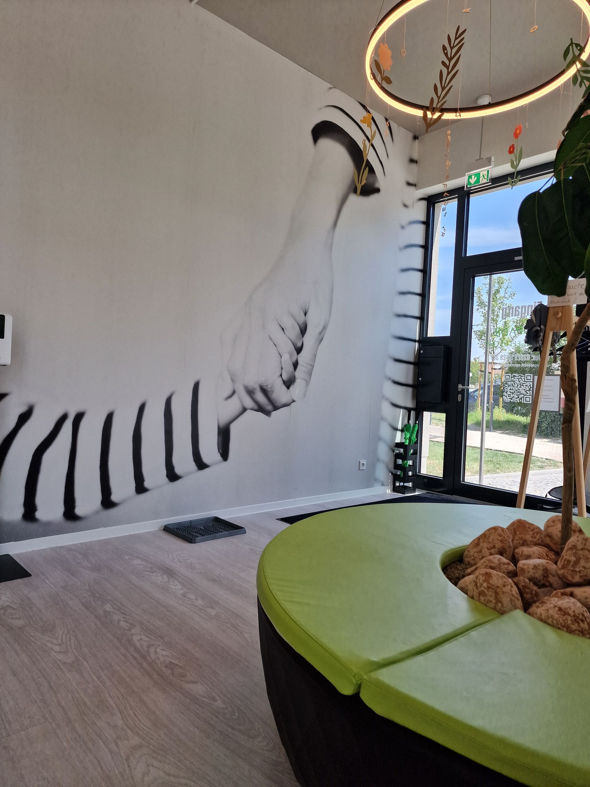 Ein hell erleuchteter Büroraum mit Schreibtisch, Stuhl und zwei Spiegeln. Spielzeug liegt auf einem grünen Teppich.