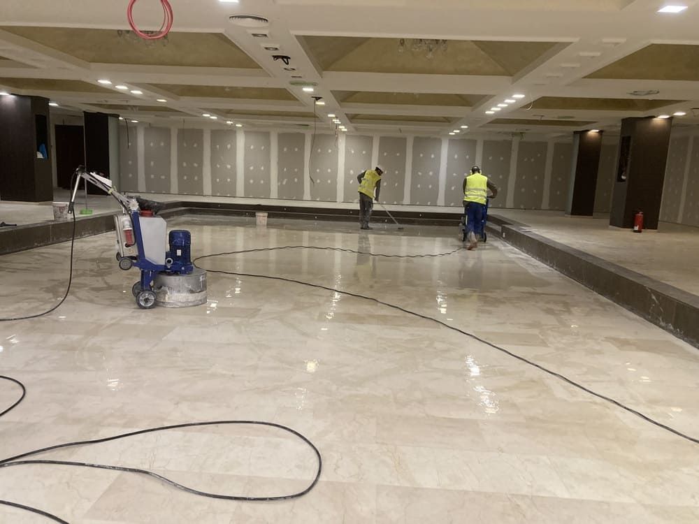 Un grupo de hombres está limpiando un piso de mármol en una habitación grande.
