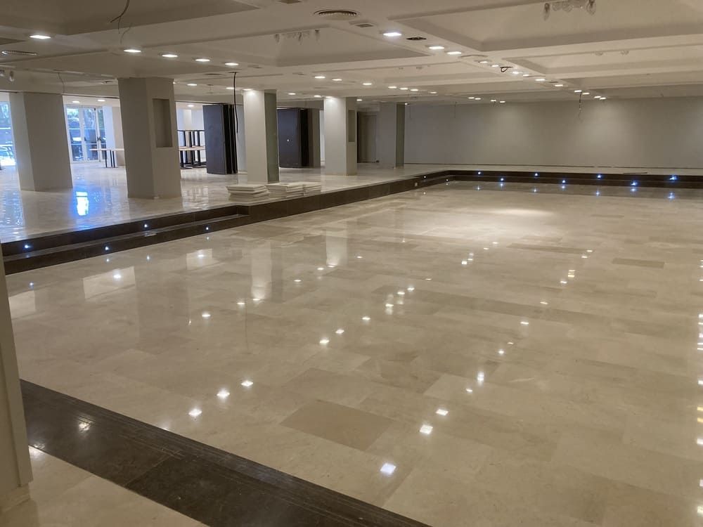 Una gran habitación vacía con suelo de mármol y columnas.