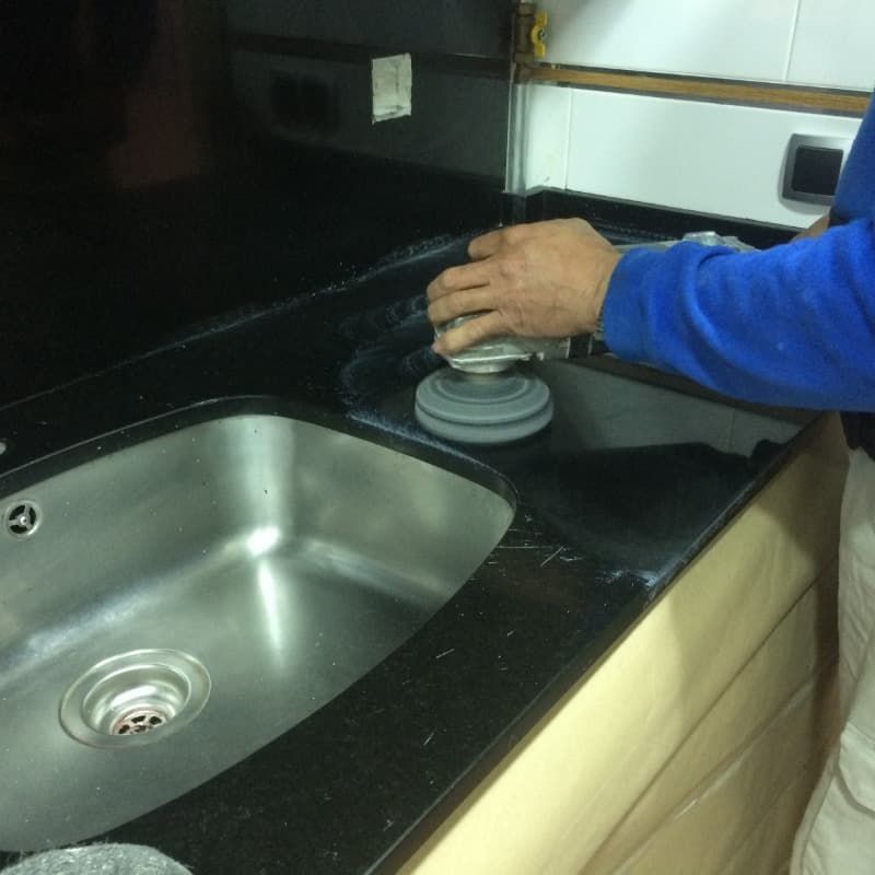 Un hombre con una camisa azul está limpiando un fregadero.