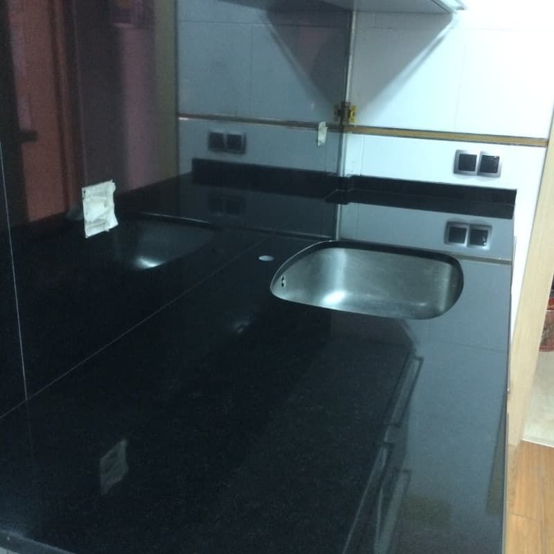 Una cocina con encimera negra y fregadero de acero inoxidable.