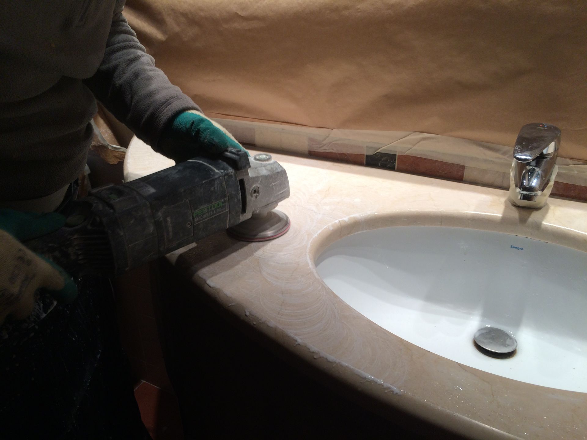 Una persona está usando una amoladora en el lavabo del baño.