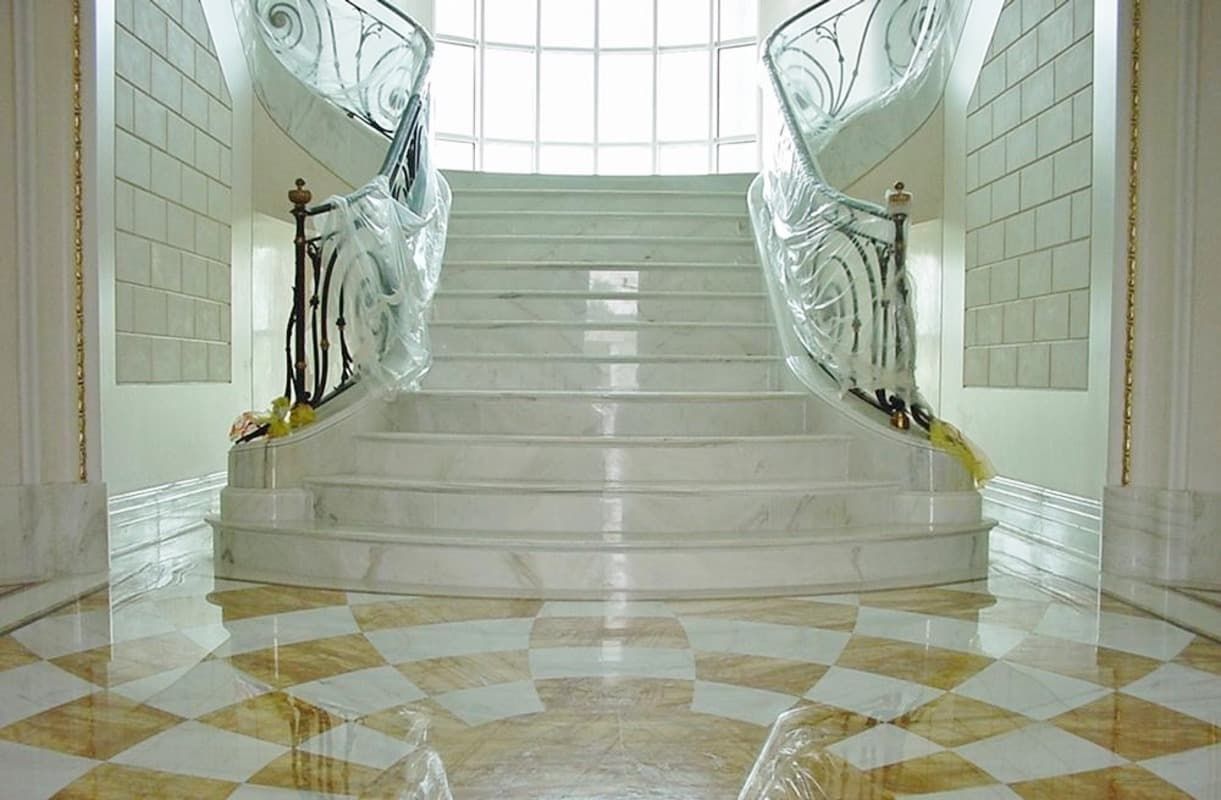 Una escalera con suelo ajedrezado y una ventana al fondo.