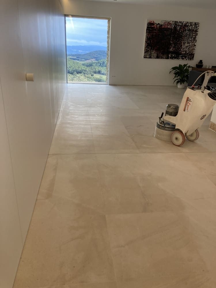 Una máquina está puliendo un piso de baldosas en una sala de estar.