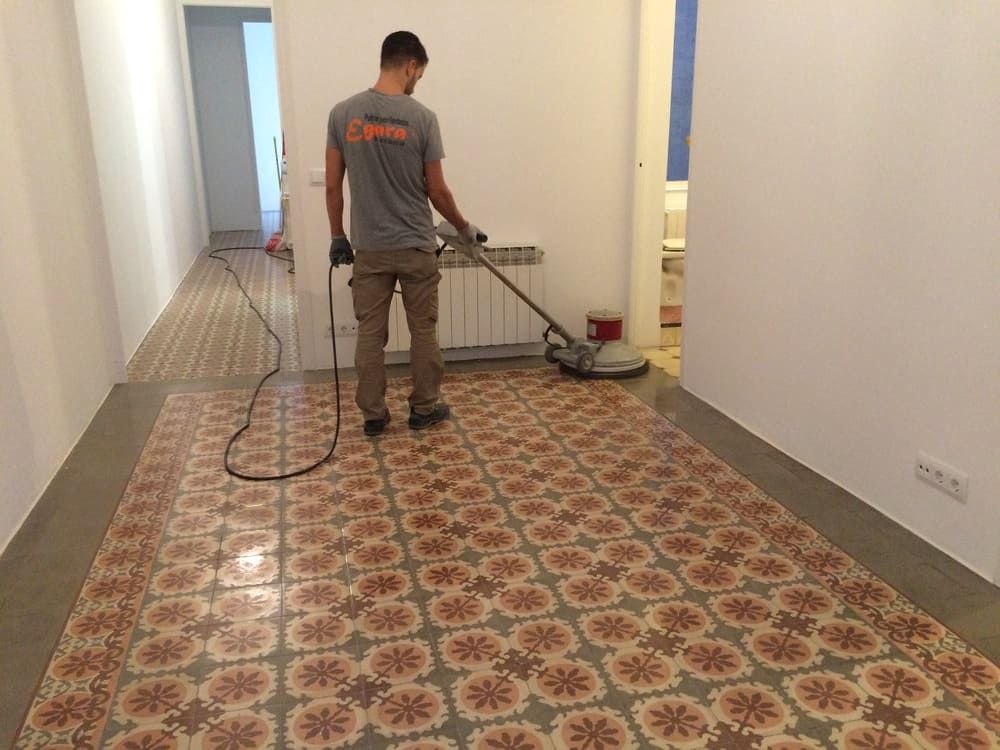 Un hombre está limpiando un piso de baldosas con una aspiradora.