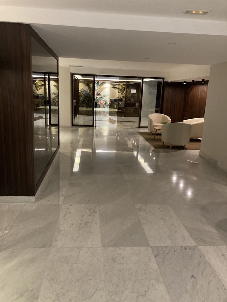 Un gran pasillo con suelo de mármol y sillas.