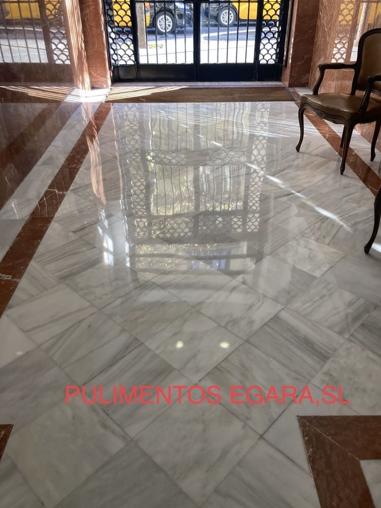 Un pasillo con suelo de mármol y una silla.