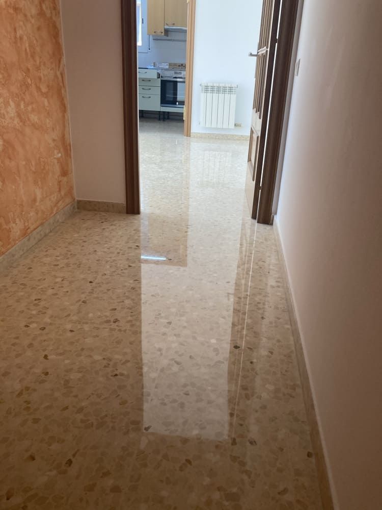 Un pasillo que conduce a una cocina con un suelo brillante.