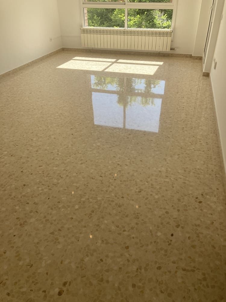 Una gran habitación vacía con suelo de mármol y una ventana.