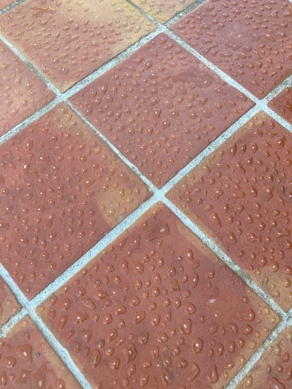 Un primer plano de un suelo de baldosas con gotas de agua sobre él.