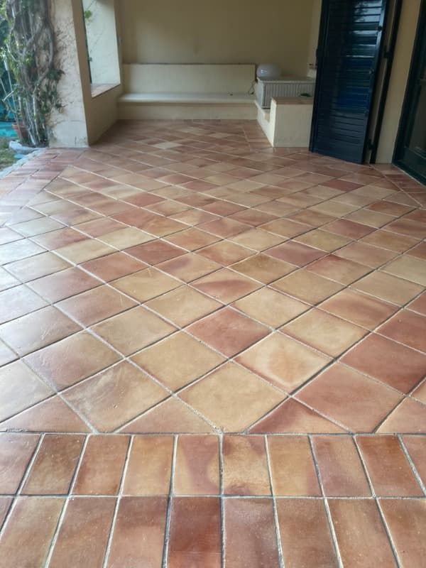Un patio con suelo de baldosas y un banco al fondo.