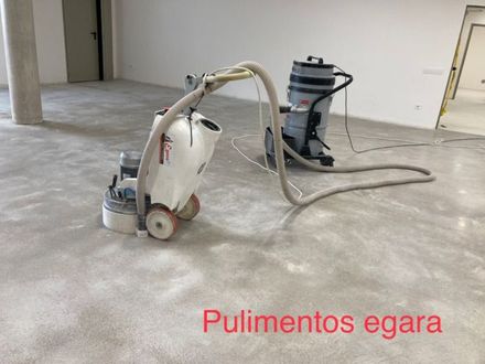 Una aspiradora está colocada sobre un suelo de hormigón al lado de otra aspiradora.