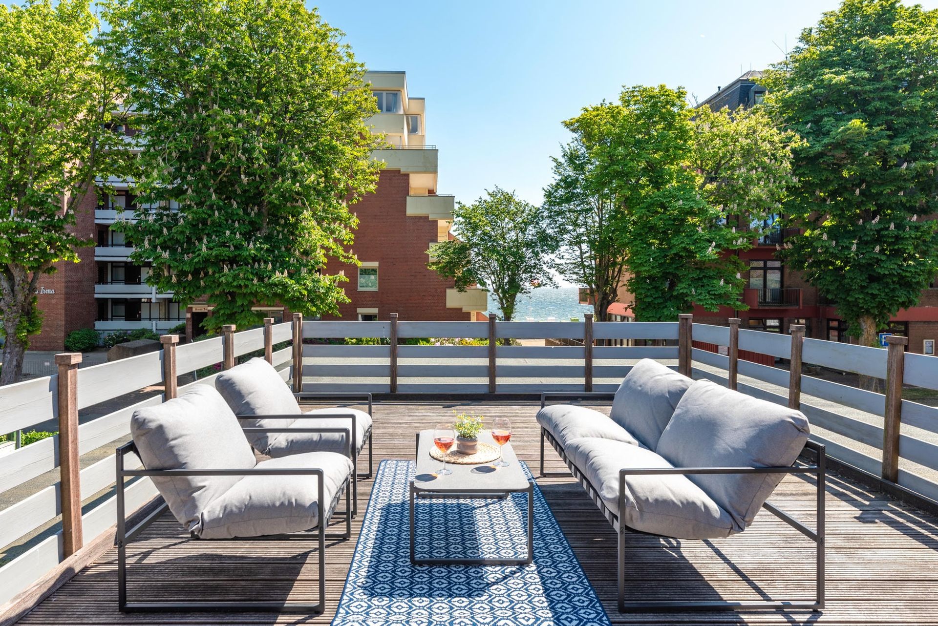 Große Dachterrasse von Utes Huus in Wyk auf Föhr mit Lounge-Möbeln, Blick auf Bäume und seitlichem Meerblick