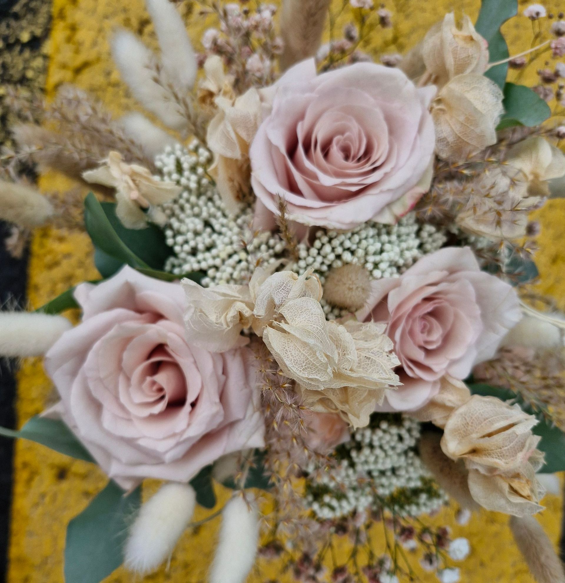 Un bouquet avec trois roses et des fleurs séchées