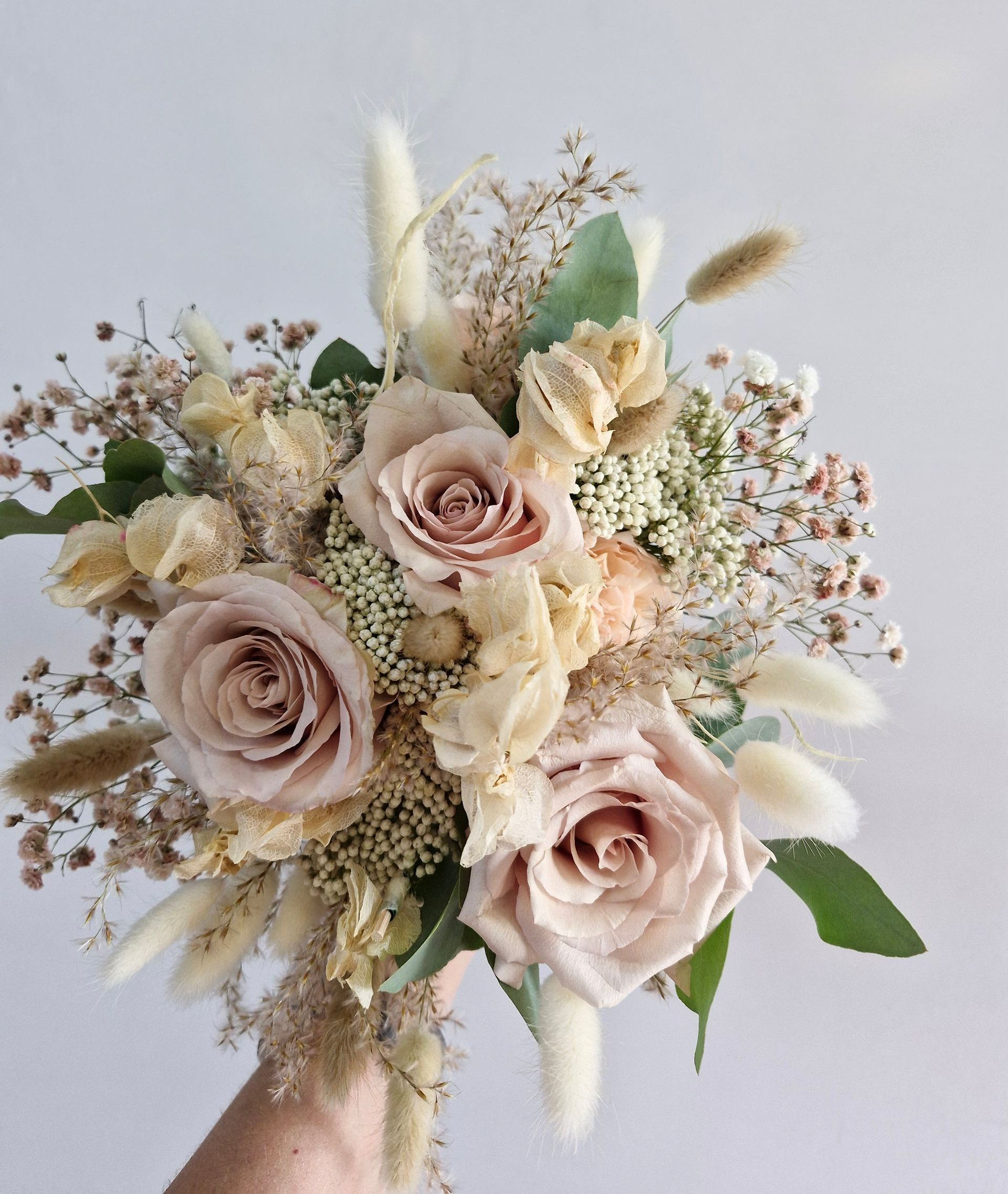 Un bouquet de roses couleur pastel tenu d'une main