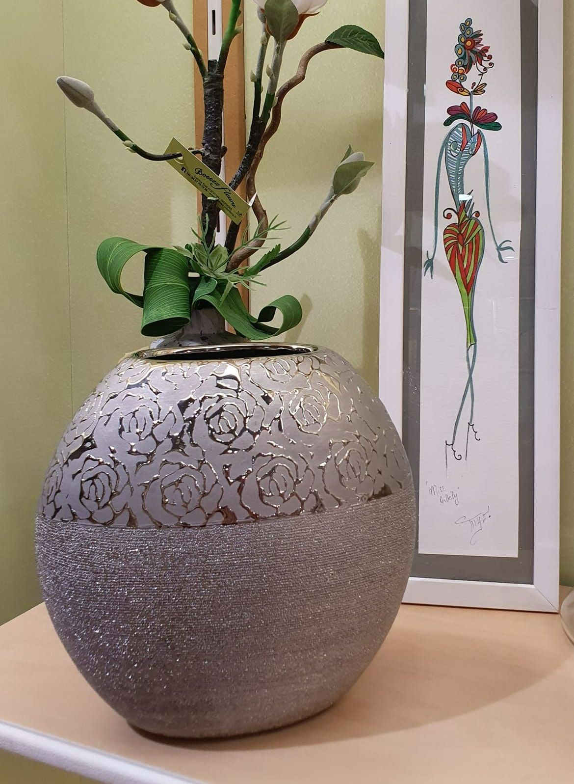 Un vase gris et rond devant un dessin