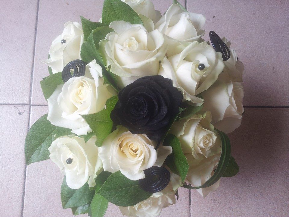 Une rose noire au milieu de roses blanches