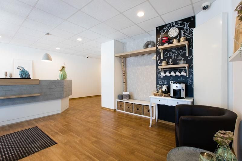 Ein Wartezimmer mit einem Tisch und Stühlen und einer Tafel an der Wand.