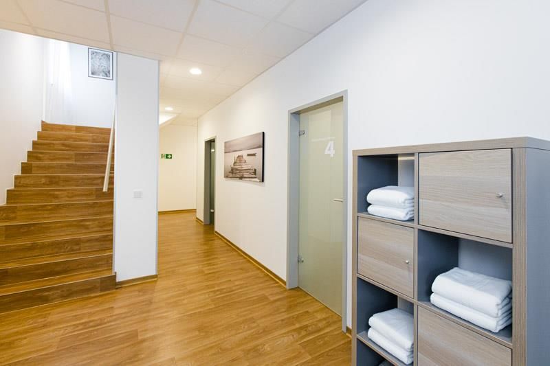 Ein Flur mit Holzboden und Holztreppe und einem Regal mit Handtüchern darauf.