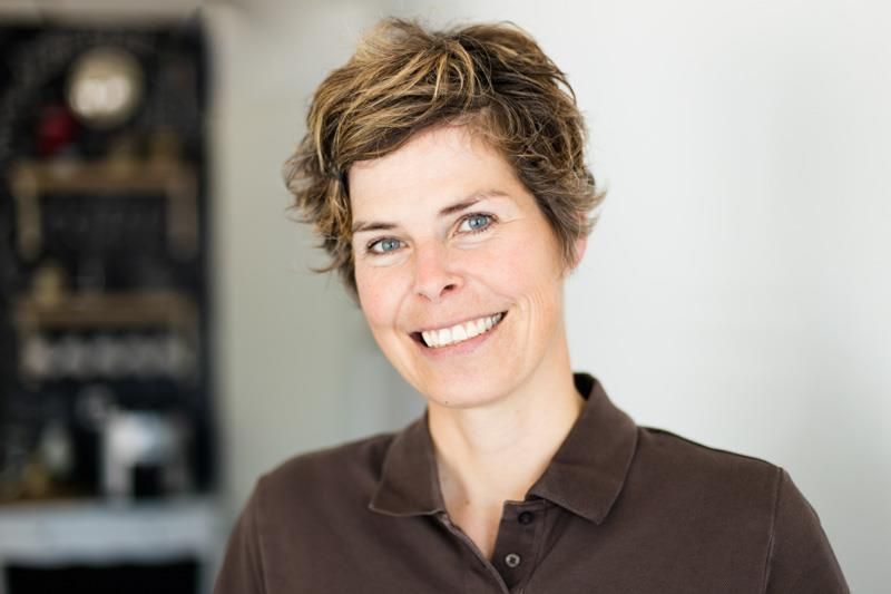 Eine Frau in einem braunen Hemd lächelt in die Kamera.