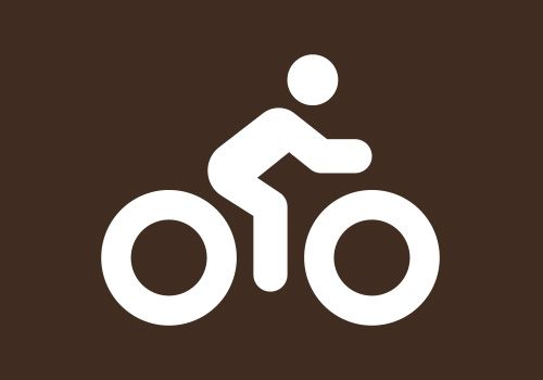 Ein weißes Symbol einer Person, die auf einem braunen Hintergrund Fahrrad fährt.