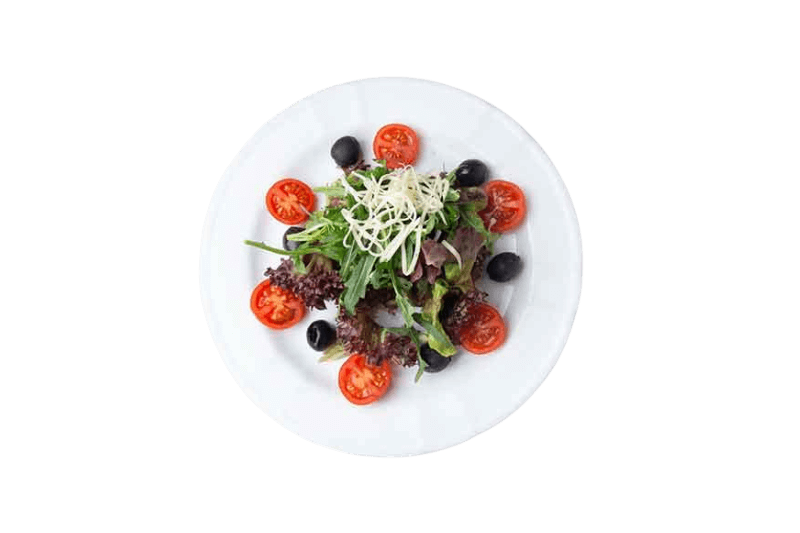 Salat auf weißem Teller mit Tomaten, Oliven und geriebenem Käse.