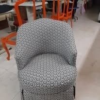 Un sillón auxiliar con forma de barril, tapizado en una tela geométrica en blanco y negro, situado en una sala de exposición.