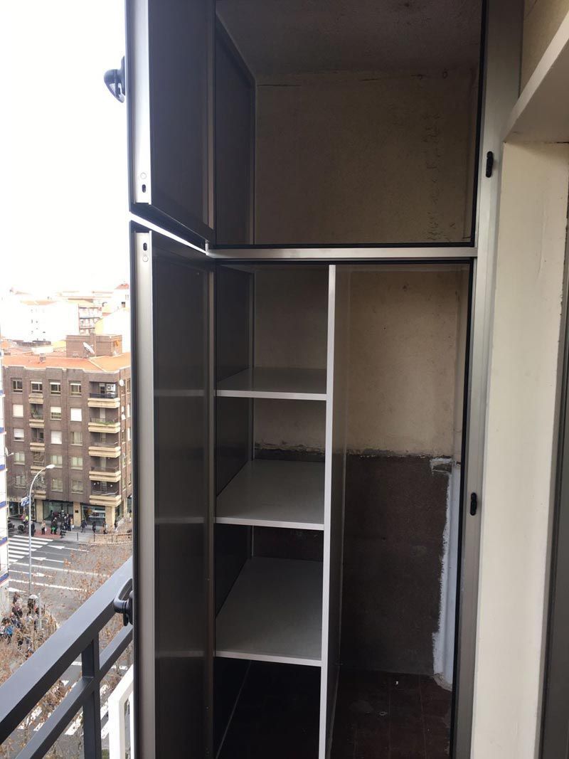 Un armario con estantes y un balcón al fondo.