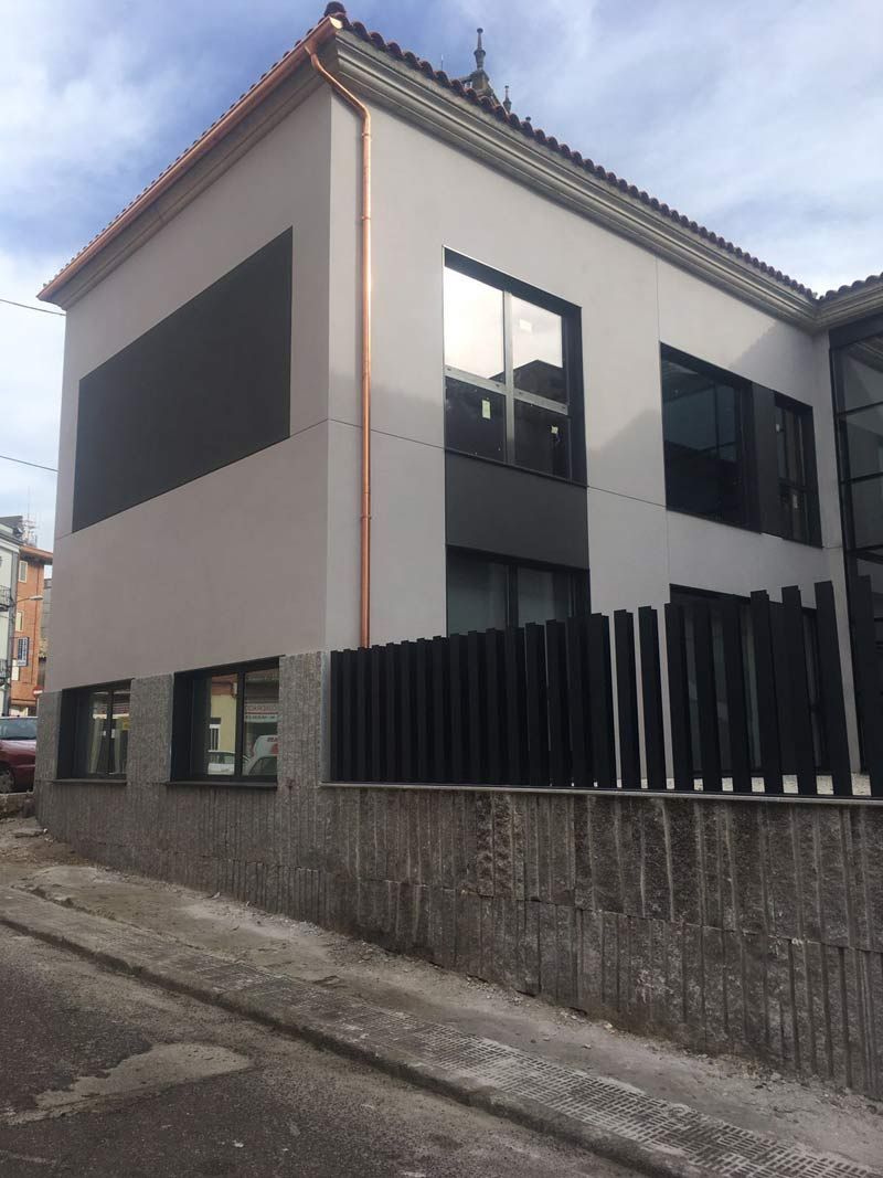 Un gran edificio blanco con una valla negra delante.