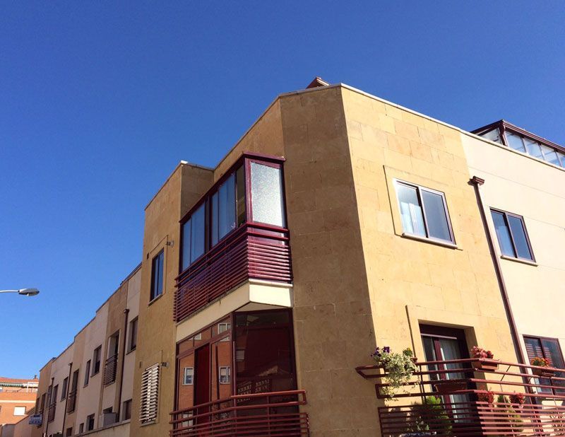 Un edificio con un balcón y un cielo azul al fondo.