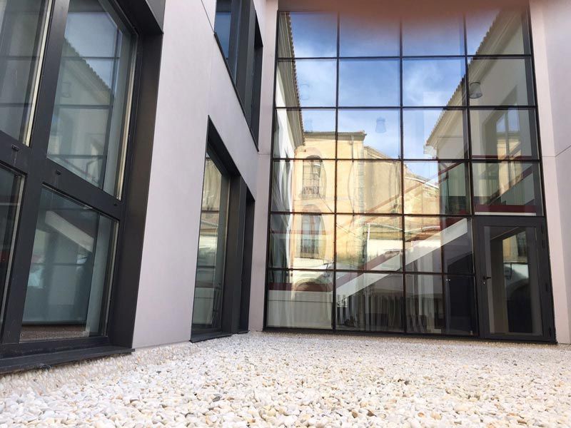 Un edificio con muchas ventanas y grava delante.