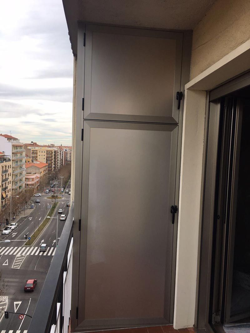 Un balcón con puerta de acero inoxidable y vista a la ciudad.