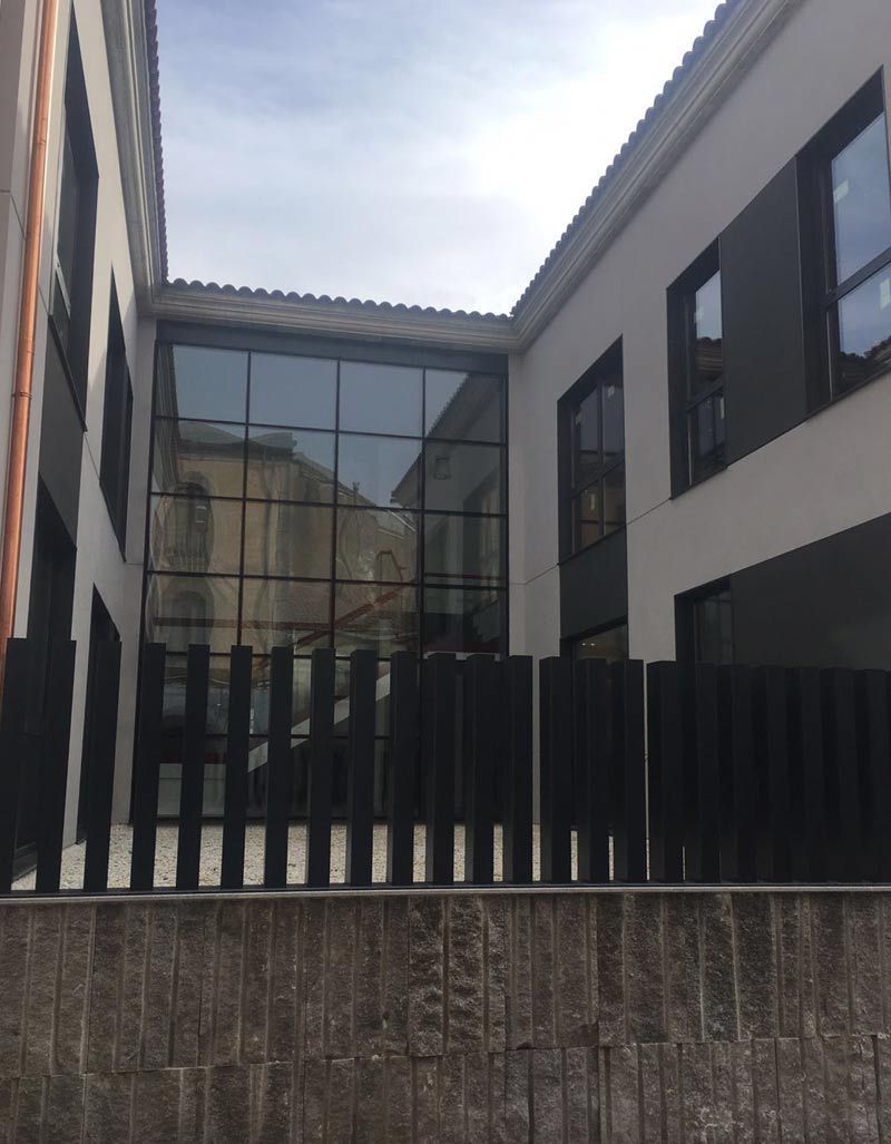 Un edificio con muchas ventanas y una valla negra.