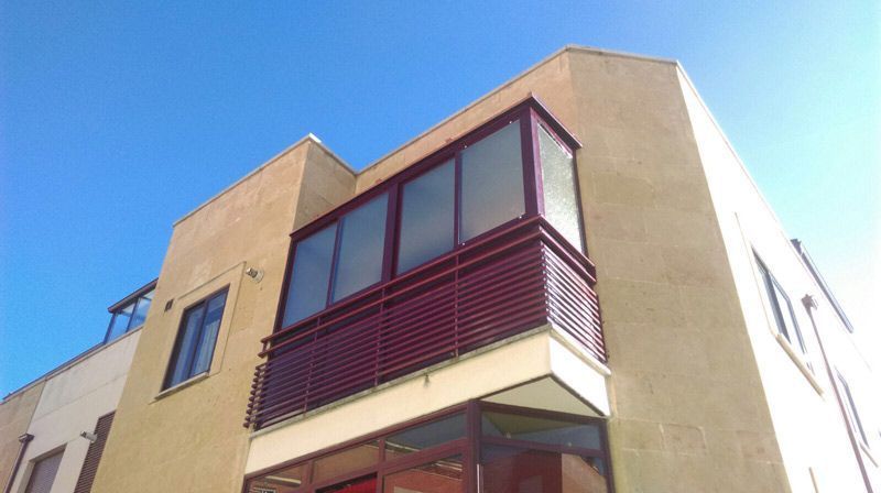 Un edificio con un balcón y un cielo azul al fondo.