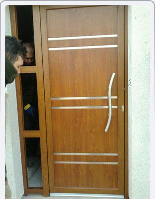 Un hombre mirando hacia una puerta de madera con manija de acero inoxidable.