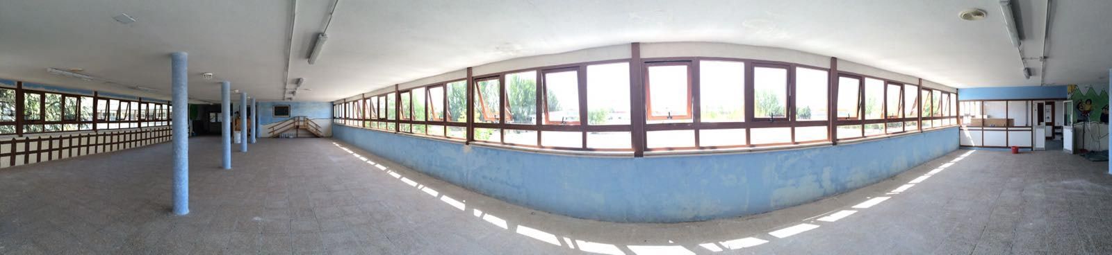 Un largo pasillo con una pared azul y muchas ventanas.