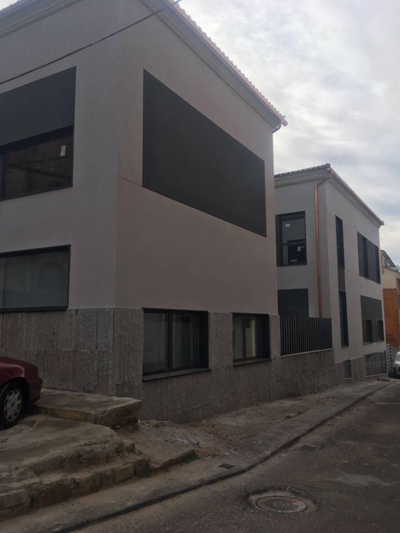 Un edificio con un coche rojo aparcado delante.