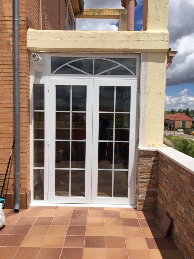 Un balcón con una puerta blanca y una pared de ladrillo.