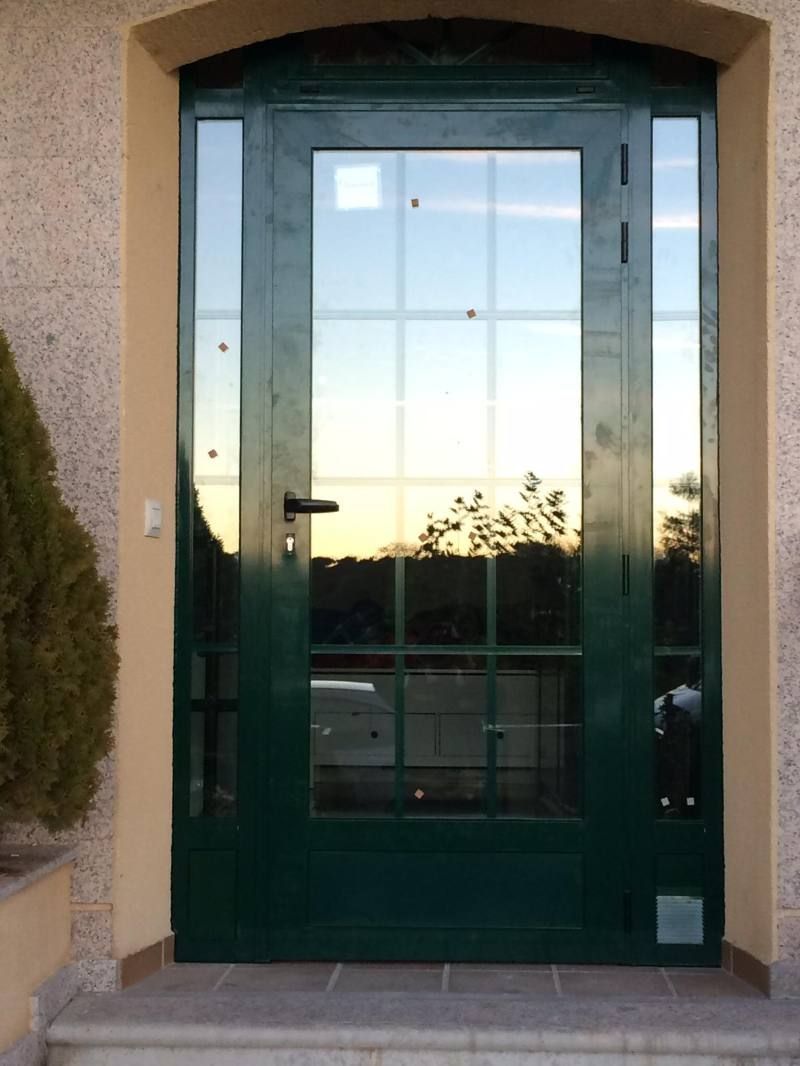 Una puerta verde con un reflejo de árboles en ella.