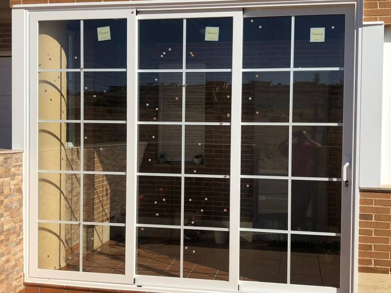 Una puerta corrediza de vidrio blanca con una pared de ladrillos al fondo.