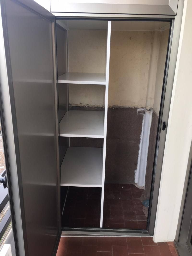 Un armario de acero inoxidable con estantes y una puerta.