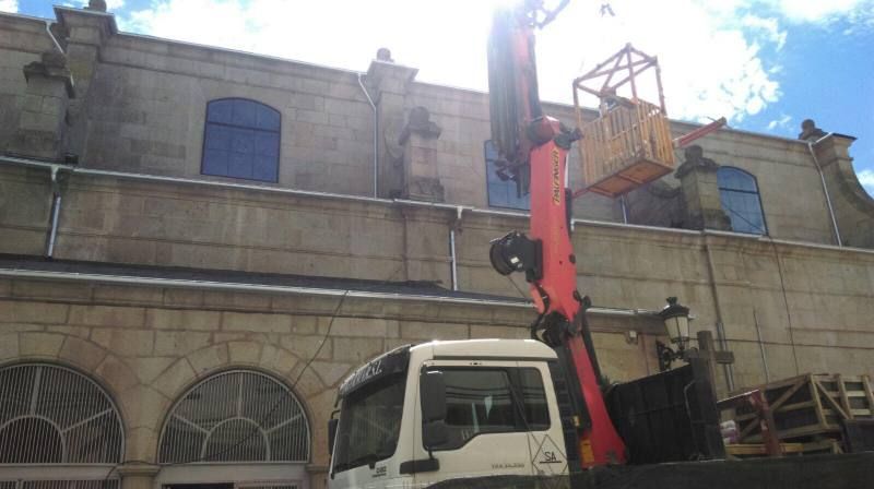 Un camión con una grúa acoplada está estacionado delante de un edificio.
