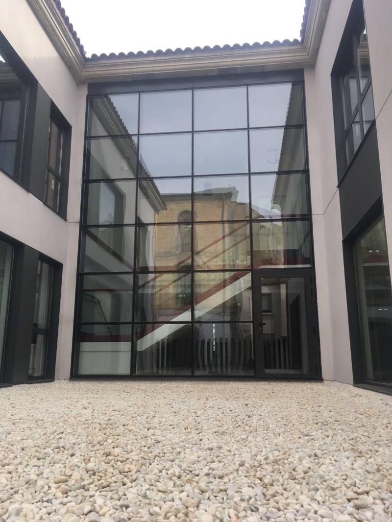 Un edificio con muchas ventanas y suelo de grava.