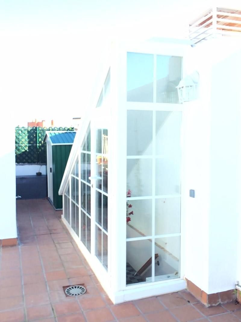 Un edificio blanco con un cobertizo verde al fondo.