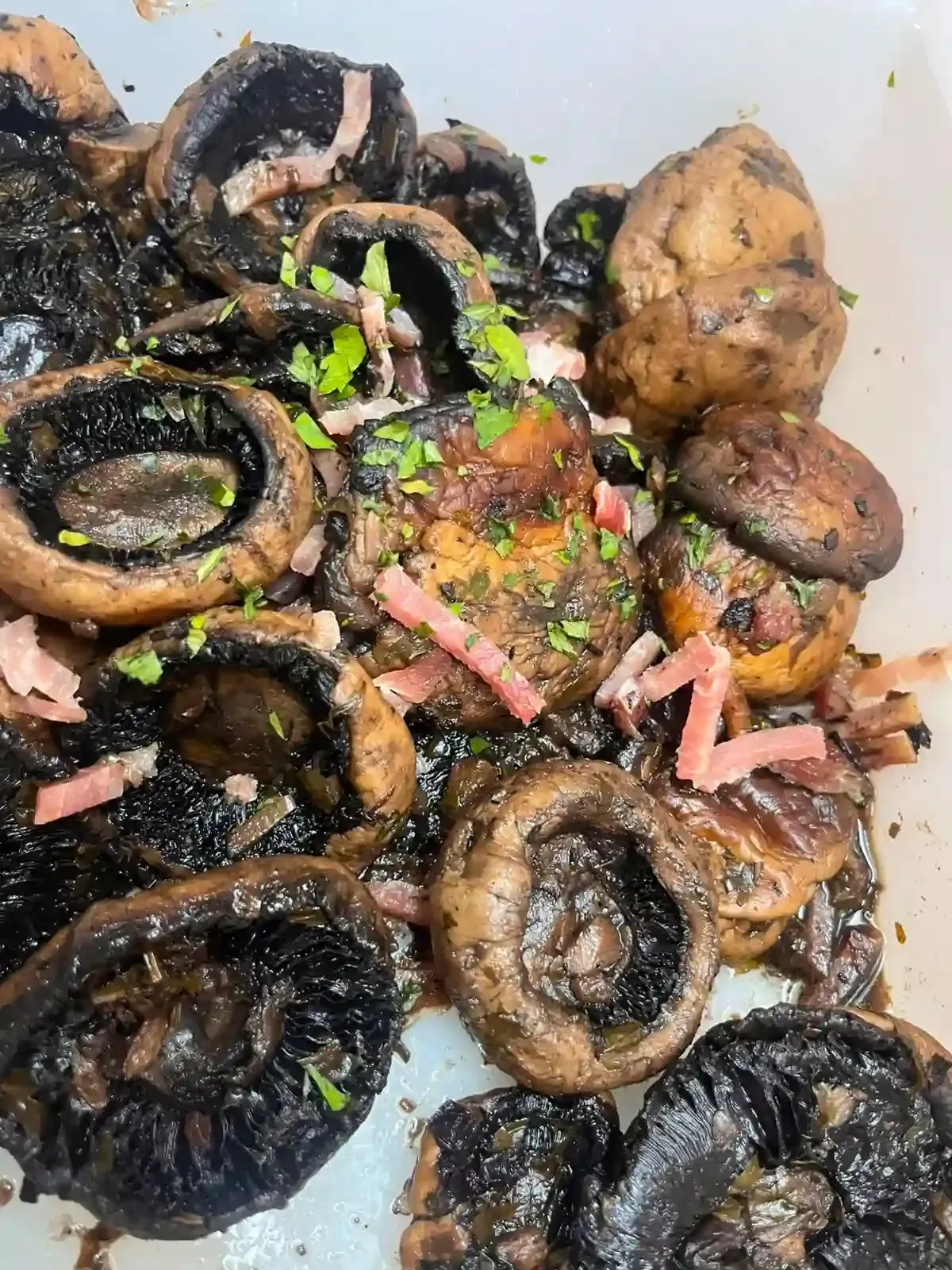 Surtido de champiñones y verduras a la parrilla en primer plano, con trozos chamuscados y hierbas encima.