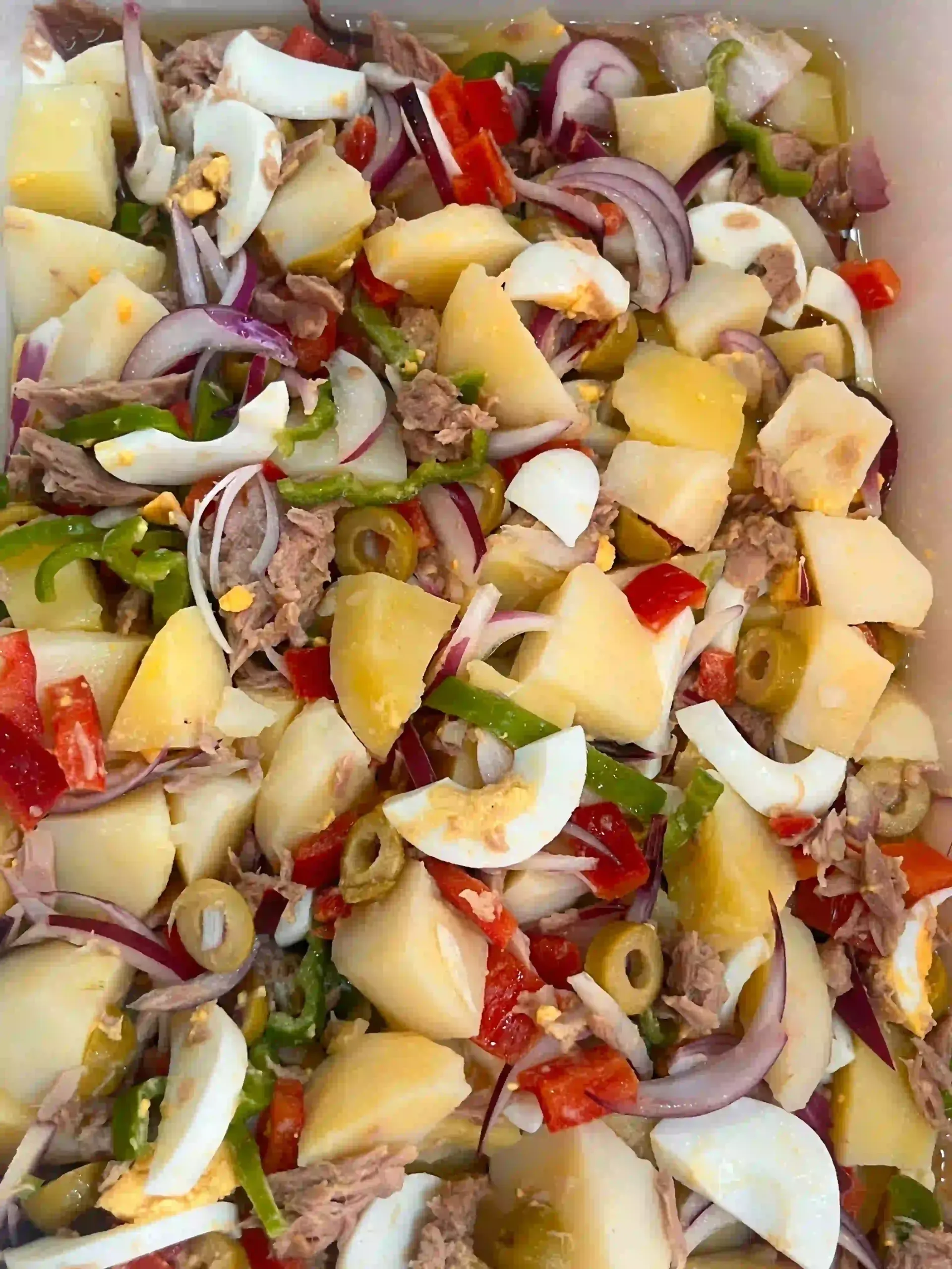 Ensalada picada colorida con papas, cebolla morada, huevos, tomates y pimientos verdes.