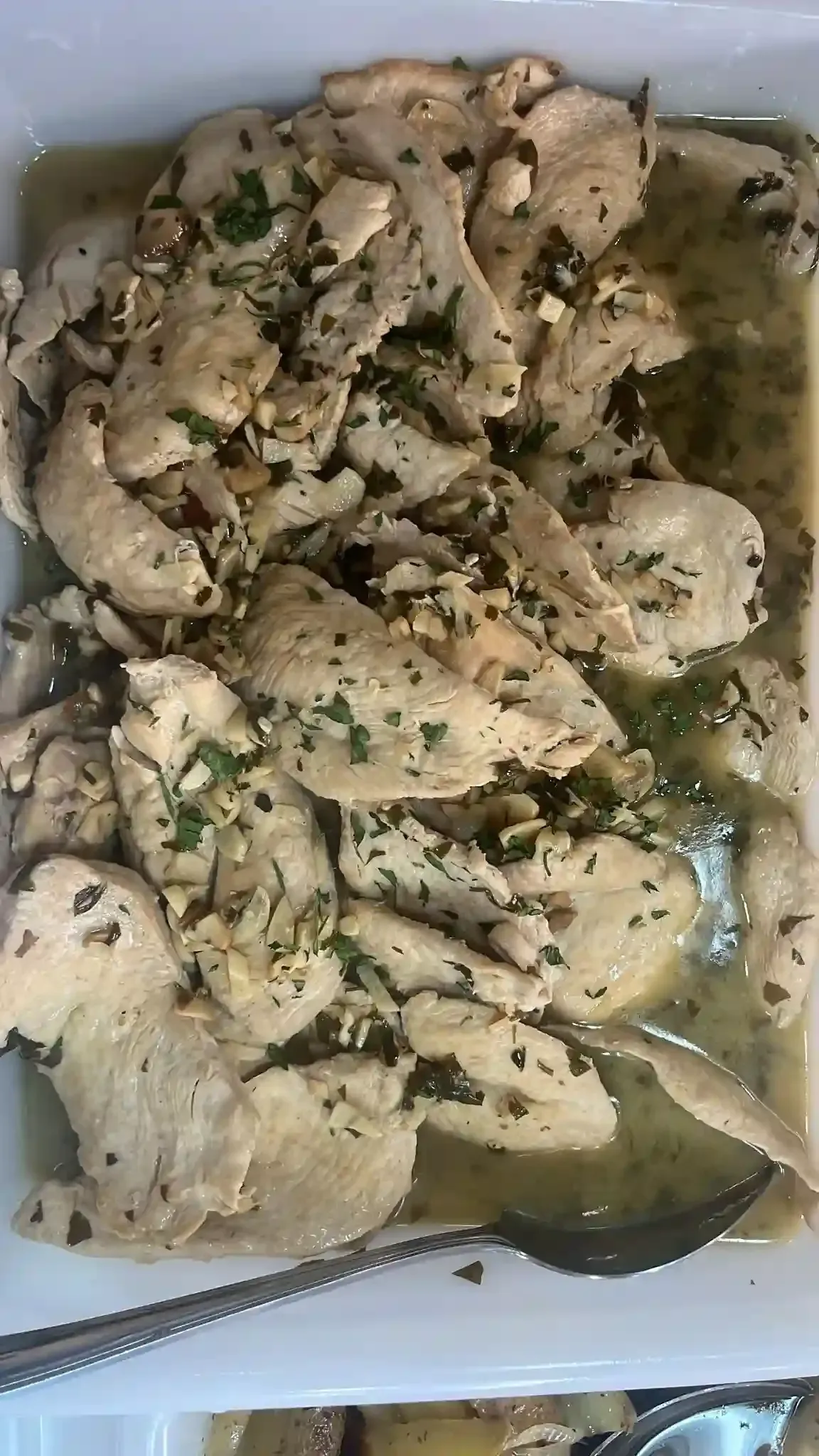 Trozos de pollo sazonados en un plato con salsa verde y un tenedor en la esquina.